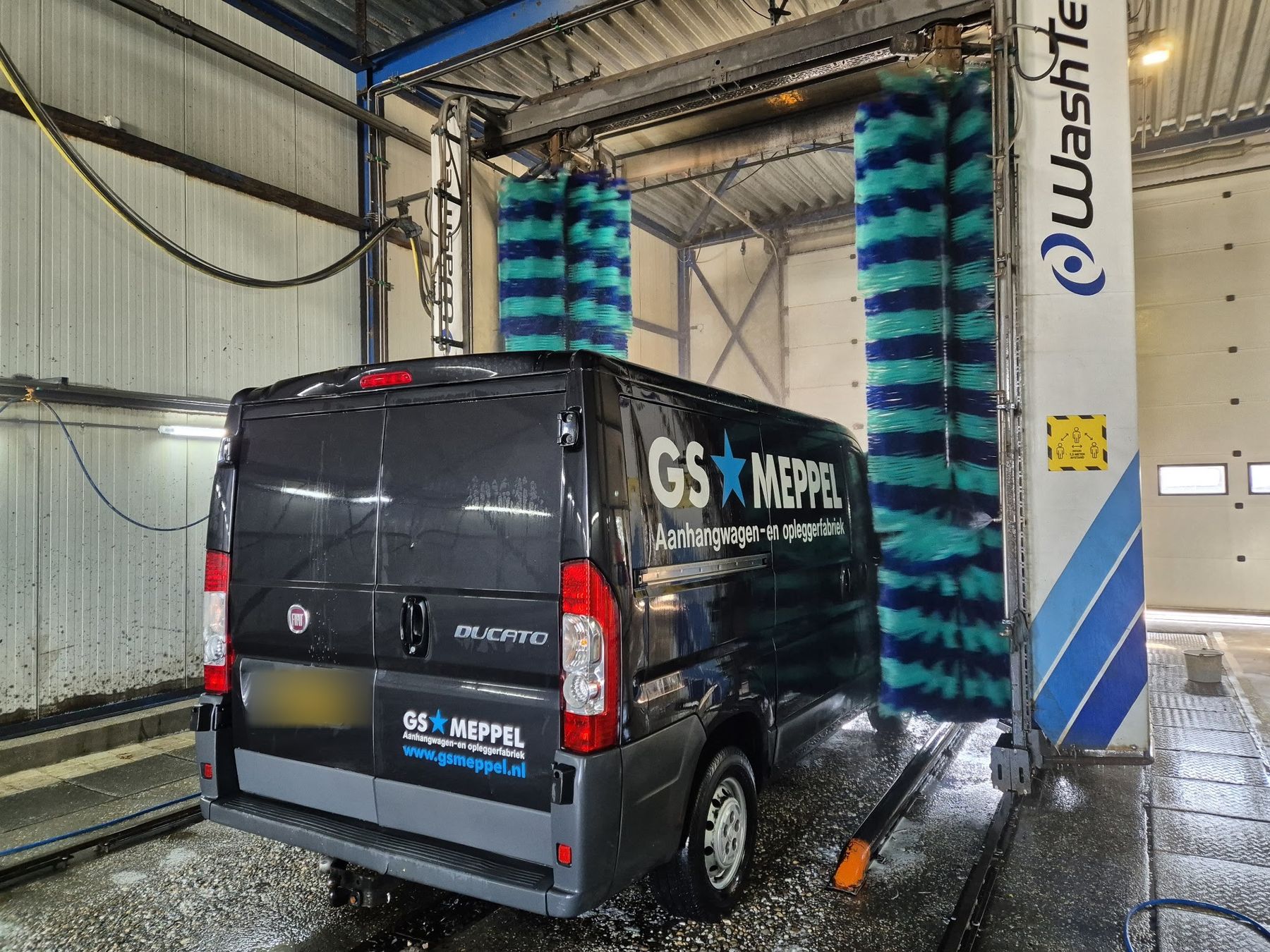 Een grijze bestelbus onder de borstelinstallatie