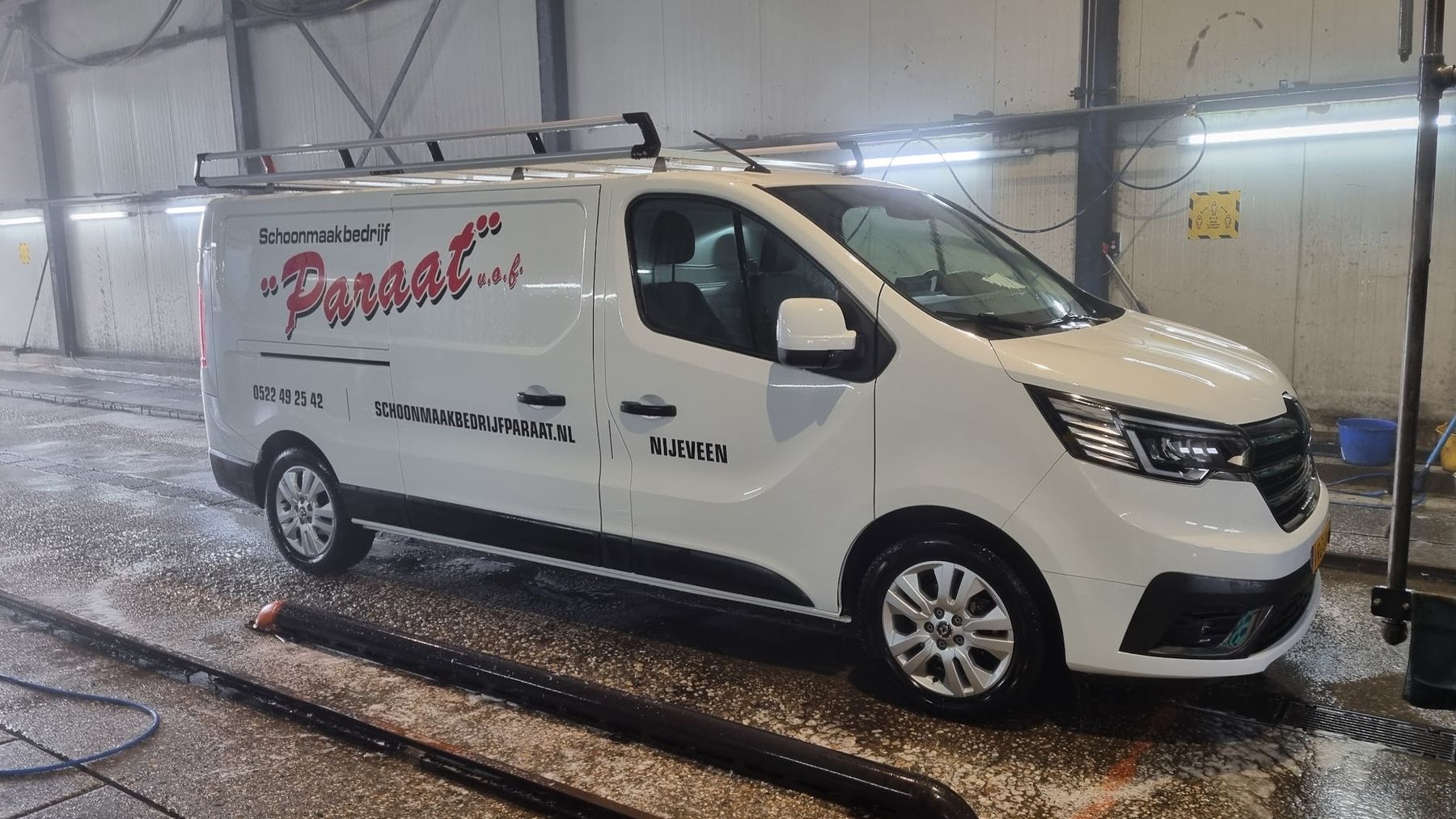 Een witte bestelbus met imperiaal in de wasstraat